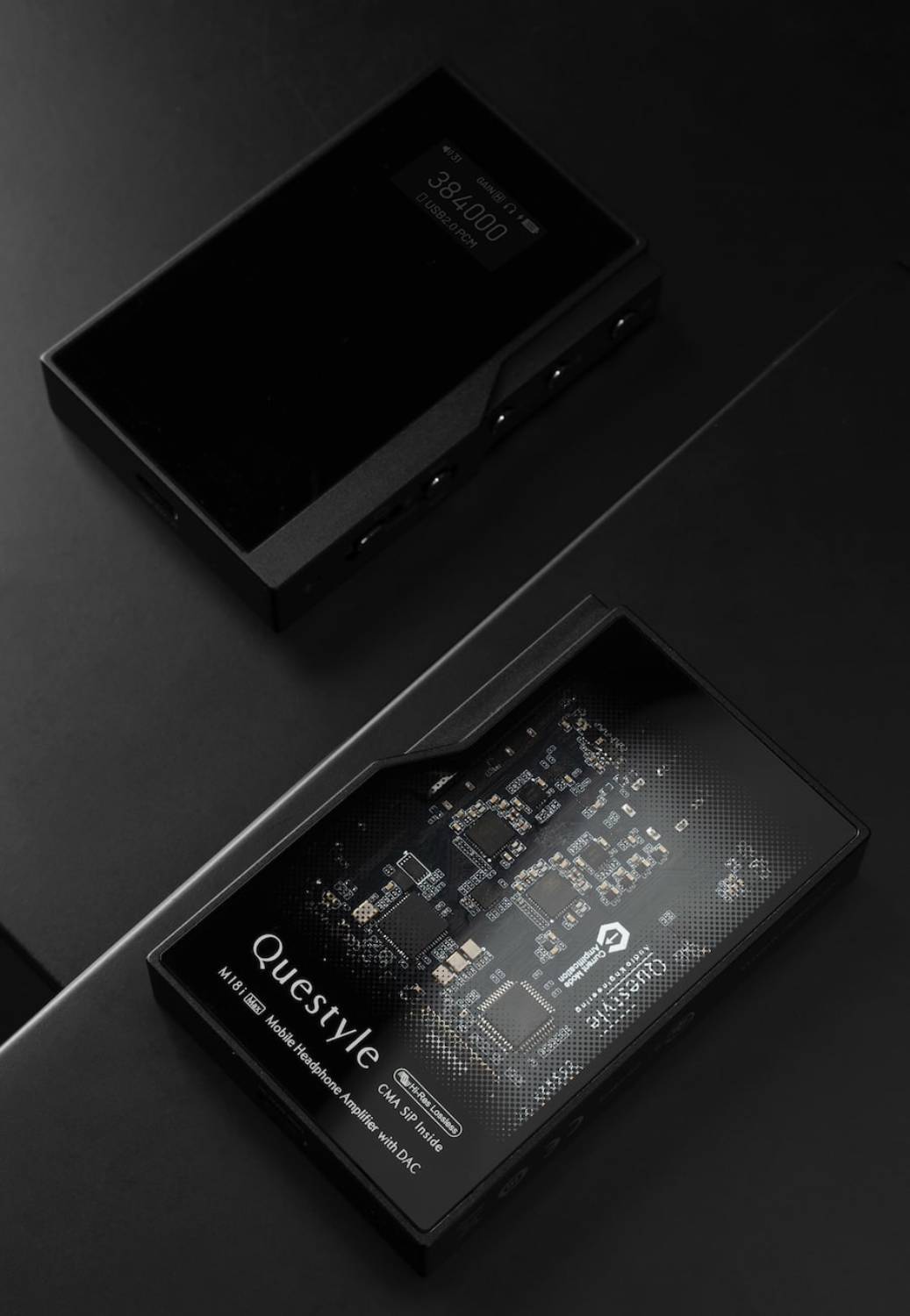 Deux Questyle M18i MAX disposés en diagonale sur fond ardoise noir, vue de face en haut avec écran OLED haute densité affichant 384000 GAIN L USB2.0 PCM et icône batterie, vue de dos en bas avec verre semi-transparent qui dévoile le PCB et les modules SiP, inscriptions Questyle M18i Max Mobile Headphone Amplifier with DAC, Hi-Res Lossless, CMA SiP Inside et logo Current Mode Amplification