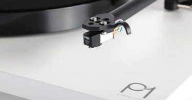Gros plan macro sur le diamant elliptique Rega Carbon Pro monté sur la cellule MM Carbon noire d'une platine vinyle Rega Planar 1 finition blanche, cantilever et fils de cellule visibles, bras de lecture RB110 en arrière-plan