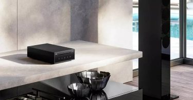 Lecteur CD Revox Studiomaster CD100 en finition noire posé sur une console en marbre clair dans un intérieur design contemporain, avec colonne Revox visible à droite et piscine en arrière-plan
