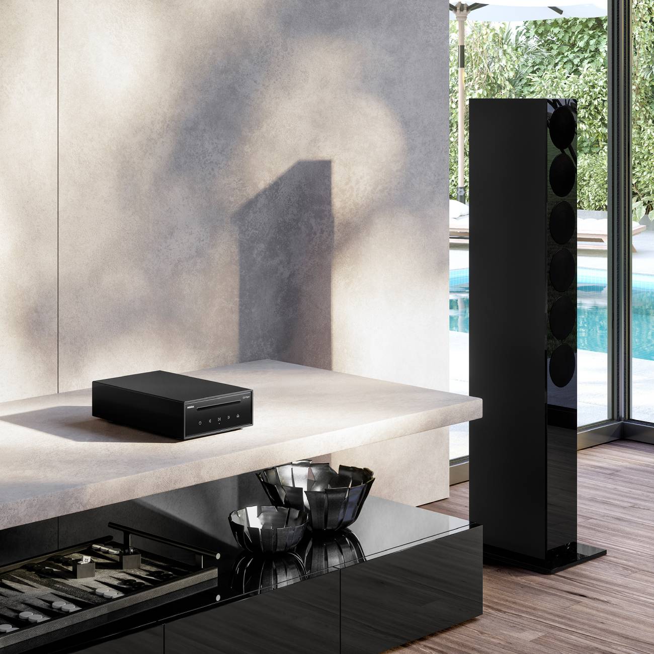 Lecteur CD Revox Studiomaster CD100 noir posé sur console en marbre clair, avec colonne enceinte Revox haute brillance à droite, vue d'écosystème complet dans intérieur design contemporain avec piscine et terrasse en arrière-plan