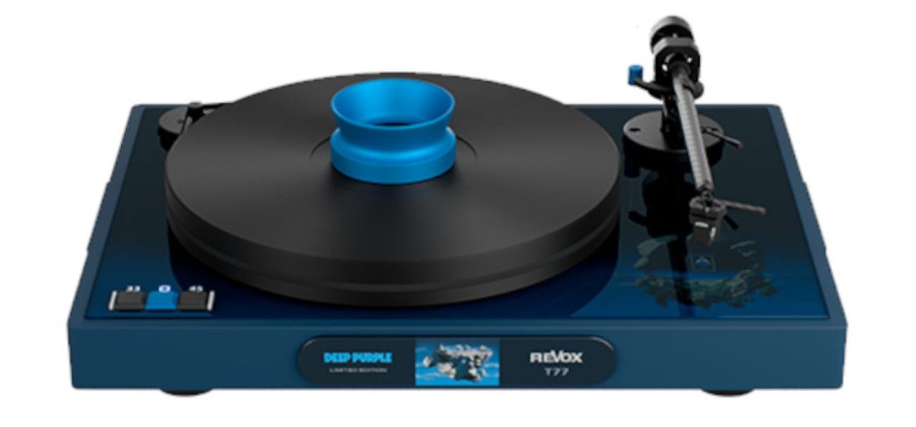 Vue de trois-quarts officielle de la platine vinyle Revox T77 Deep Purple Limited Edition en finition bleu nuit profond, équipée de son palet de centrage bleu turquoise, plateau noir mat, bras de lecture droit avec cellule, sélecteurs de vitesse 33 et 45 tours par minute en bas à gauche, et plaque d'identification DEEP PURPLE LIMITED EDITION REVOX T77 sur la façade