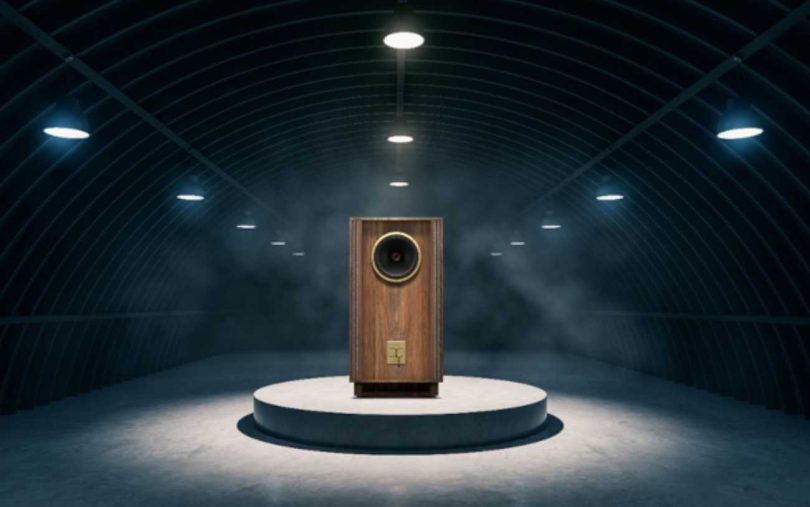 Enceinte Tannoy Prestige Gold Reference édition anniversaire 100 ans en finition noyer huilé, mise en scène dans un loft industriel avec briques rouges et grandes baies vitrées, haut-parleur Dual Concentric 15 pouces visible derrière le pavillon avant.