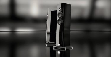 Paire d'enceintes colonne TIDAL Piano Classic en finition laque piano Midnight Black, vues de trois quarts sur sol miroir noir. Tweeter céramique noire 1,2 pouce et deux mid-woofers crystalid 7 pouces visibles en façade, embase acier inoxydable et isolators apparents.