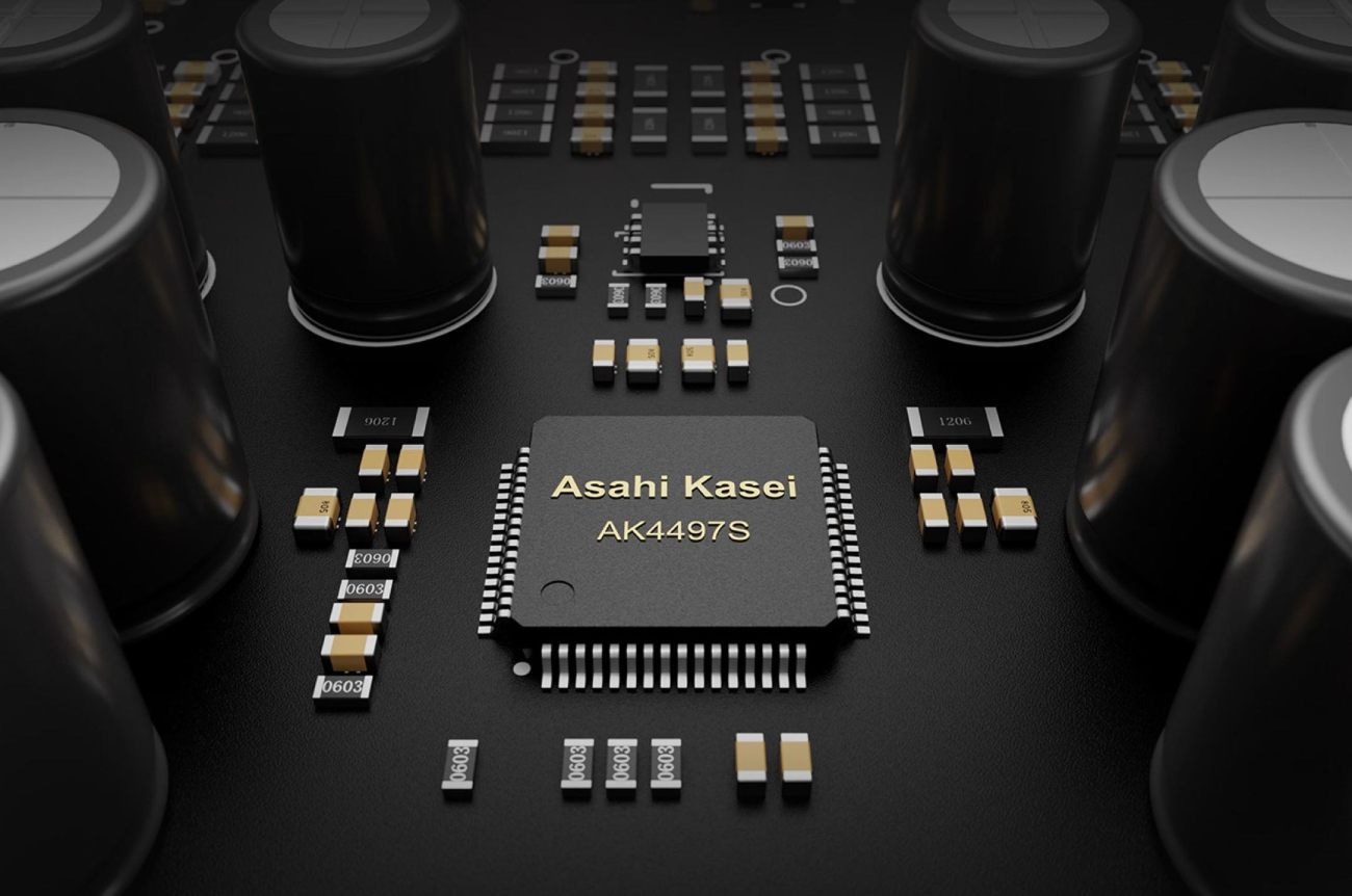 Vue macro de la puce de conversion numérique-analogique Asahi Kasei AK4497S au format QFP sérigraphiée en doré sur fond noir, entourée de condensateurs électrolytiques noirs cylindriques, de résistances CMS 1206 et 0603 dorées, et de composants discrets du circuit analogique du TOPPING E50II