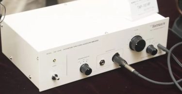 Amplificateur casque Uesugi TAP-101HP en chassis blanc avec interrupteur d'alimentation, sélecteur d'impédance LOW MID HIGH, sortie casque jack 6.3 mm et XLR 4 broches, et boutons de volume, présenté au Spring Headphone Festival 2026 de Tokyo