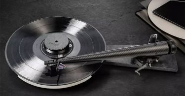 Bras de lecture Wand Dark-Light 12 pouces en fibre de carbone tressée matt noir installé sur une platine vinyle audiophile, montrant le tube tronconique à Musical Taper avec son diamètre croissant vers le pivot arrière et son porte-cellule en aluminium à l'avant, surface en ardoise sombre