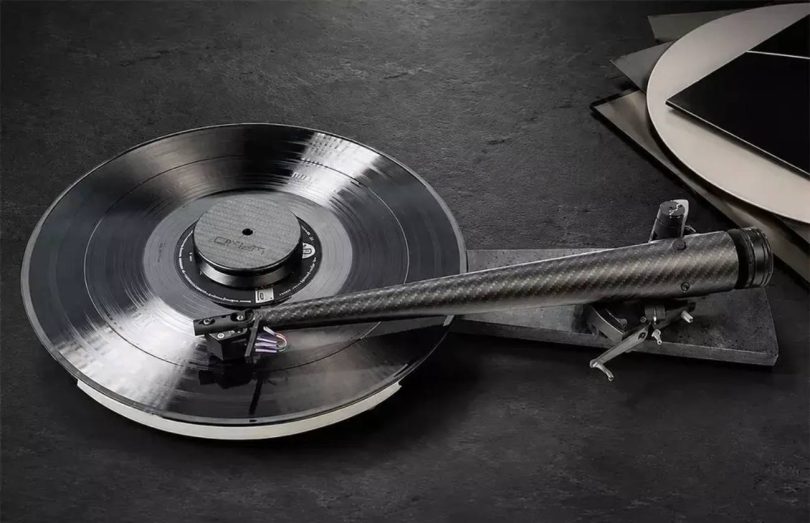 Bras de lecture Wand Dark-Light 12 pouces en fibre de carbone tressée matt noir installé sur une platine vinyle audiophile, montrant le tube tronconique à Musical Taper avec son diamètre croissant vers le pivot arrière et son porte-cellule en aluminium à l'avant, surface en ardoise sombre