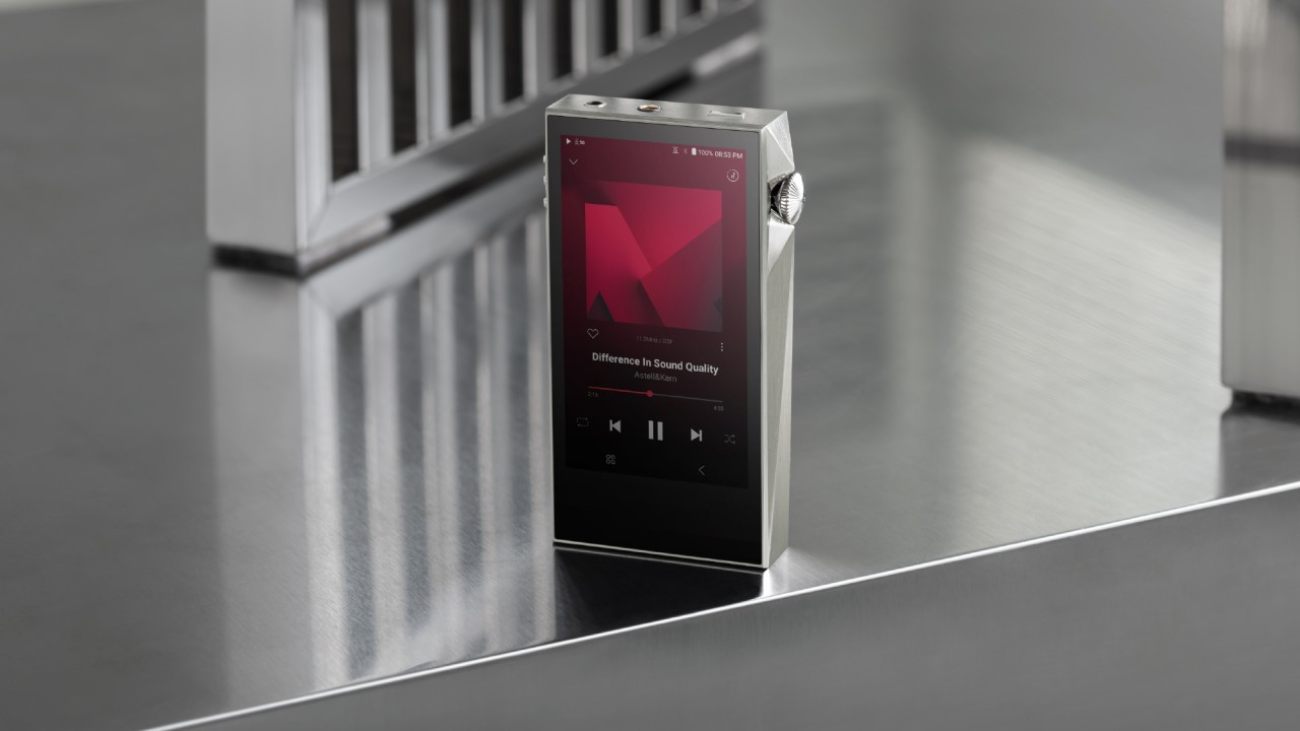 Astell&Kern A&ultima SP3000M en finition aluminium argent posé sur une surface métallique brossée, écran 4,1 pouces allumé affichant l'interface 4.5G en lecture avec le logo K rouge, molette de volume crantée visible sur le flanc droit et design diamant caractéristique de la série A&ultima