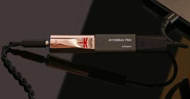 DAC USB nomade AudioQuest DragonFly Copper au boîtier plaqué cuivre avec logo libellule rouge, relié à un filtre JitterBug FMJ puis à un adaptateur DragonTail USB-C branché sur un ordinateur portable, sortie casque 3,5 mm à gauche