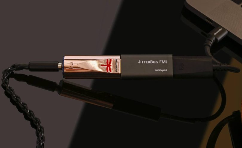DAC USB nomade AudioQuest DragonFly Copper au boîtier plaqué cuivre avec logo libellule rouge, relié à un filtre JitterBug FMJ puis à un adaptateur DragonTail USB-C branché sur un ordinateur portable, sortie casque 3,5 mm à gauche