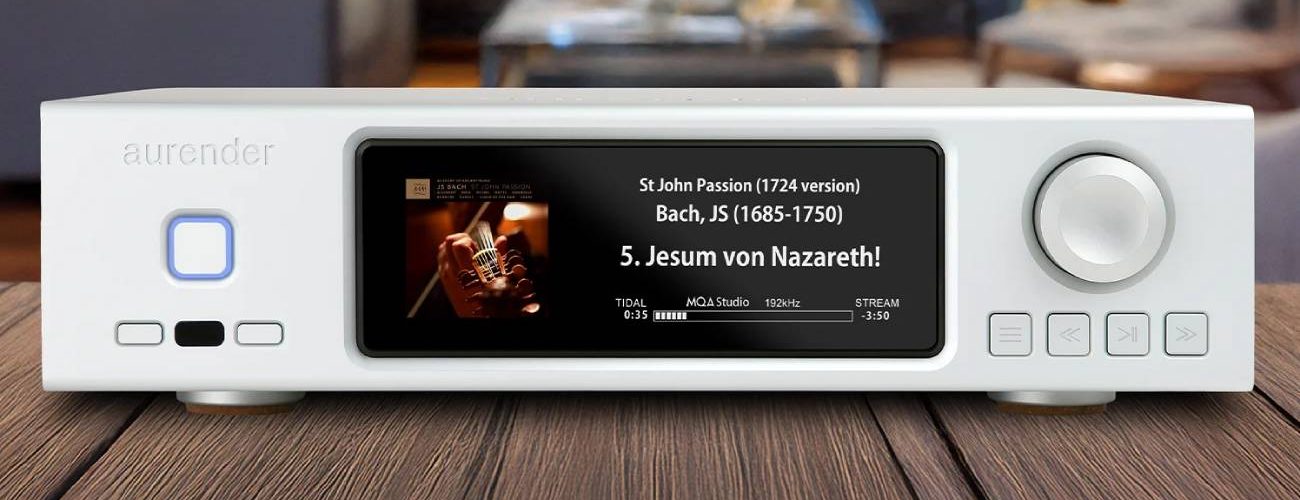 Aurender DA100, streaming DAC dual-mono AK4499 en finition blanche posé sur un plan en bois, écran IPS affichant une lecture TIDAL haute résolution, bouton de veille rétroéclairé bleu à gauche et molette de volume à droite