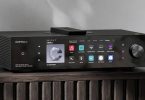 Eversolo DMP-A8 Master Gen 2 en finition noire posé sur un meuble bois, grand écran tactile 8,6 pouces affichant les services de streaming, molette de volume à droite et télécommande sur le dessus, streamer DAC préamplificateur tout-en-un