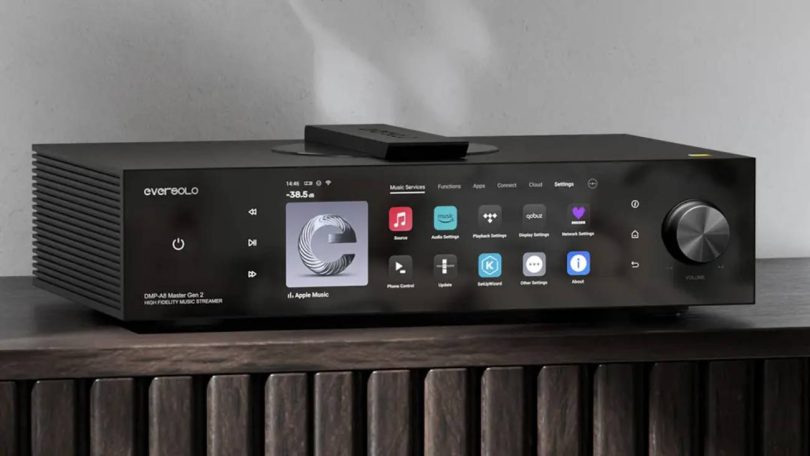 Eversolo DMP-A8 Master Gen 2 en finition noire posé sur un meuble bois, grand écran tactile 8,6 pouces affichant les services de streaming, molette de volume à droite et télécommande sur le dessus, streamer DAC préamplificateur tout-en-un