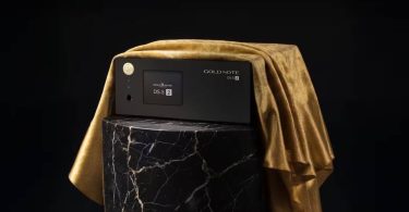 Streamer DAC Gold Note DS-5.2 en finition noire posé sur un socle en marbre noir veiné de blanc avec drapé de velours doré, façade aluminium anodisé noir avec écran tactile couleur, molette ronde dorée et logo Gold Note