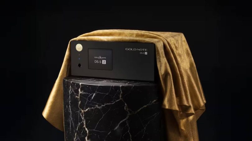 Streamer DAC Gold Note DS-5.2 en finition noire posé sur un socle en marbre noir veiné de blanc avec drapé de velours doré, façade aluminium anodisé noir avec écran tactile couleur, molette ronde dorée et logo Gold Note