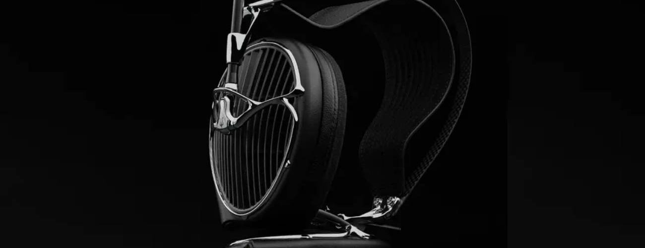 Casque audiophile ouvert Meze Audio ARTA en finition noire posé sur un socle en cuir, grille sculpturale aux lames acoustiques inclinées, arceau suspendu et driver planar magnétique MZ5 HΩ 225 ohms visible