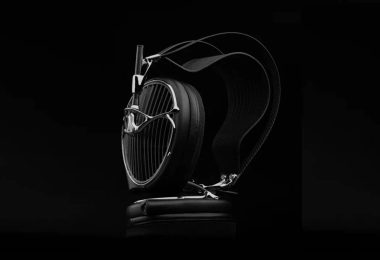 Casque audiophile ouvert Meze Audio ARTA en finition noire posé sur un socle en cuir, grille sculpturale aux lames acoustiques inclinées, arceau suspendu et driver planar magnétique MZ5 HΩ 225 ohms visible