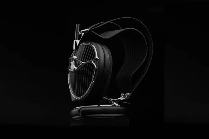 Casque audiophile ouvert Meze Audio ARTA en finition noire posé sur un socle en cuir, grille sculpturale aux lames acoustiques inclinées, arceau suspendu et driver planar magnétique MZ5 HΩ 225 ohms visible