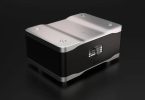 Convertisseur numérique-analogique Wadax Studio DAC au châssis noir et capot aluminium sculpté, écran de sélection de source affichant les entrées AES-EBU, RCA, BNC, Streaming, Akasa 2 et Transport, sur fond sombre