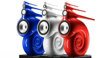Trois enceintes Bowers & Wilkins Nautilus en finition peinture sur mesure bleu, blanc et rouge, posées sur socles granit noir, dévoilant leur spirale de grave enroulée et leurs tubes effilés de médium et d'aigu