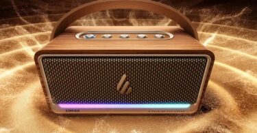 Enceinte karaoké portable Edifier K200 vue de face, caisson finition bois clair, grille métallique perforée, poignée de transport cintrée en similicuir brun, cinq boutons physiques sur le dessus et bandeau LED RGB rose et bleu en bas de façade