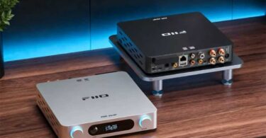 Deux amplificateurs de streaming FiiO Air Amp sur un bureau en bois : au premier plan la version argent vue de face avec son écran LCD affichant le mode STREAM et ses deux molettes rétroéclairées volume et treble, en arrière-plan la version noire vue de dos montrant le port Ethernet, les entrées USB, coaxiale et optique, les RCA Line In et le bornier haut-parleurs