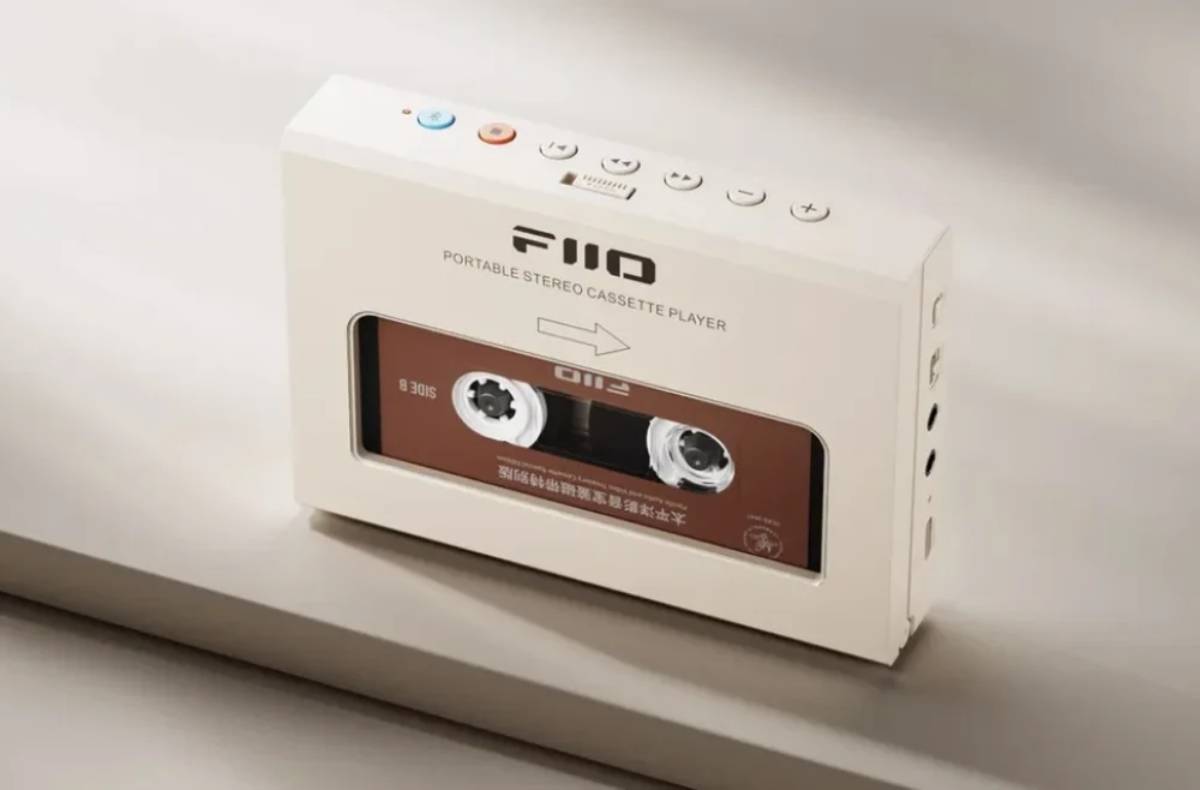 Lecteur de cassettes portable FiiO CP11 en coloris crème vu de trois quarts, logo FIIO et mention Portable Stereo Cassette Player en façade, fenêtre transparente sur une cassette brune SIDE B, boutons de transport argentés et touches Bluetooth bleue et orange sur la tranche supérieure, ports alignés sur le flanc droit