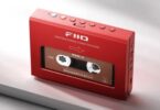 Lecteur de cassettes portable FiiO CP11 en finition rouge vu de trois quarts, fenêtre transparente laissant voir la cassette insérée, rangée de boutons de transport sur la tranche supérieure avec touche Bluetooth bleue et touche orange, connectique sur le flanc droit