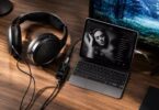 Casque circum-aural ouvert à transducteurs planar magnétiques posé sur un bureau en bois, câble détachable relié à un DAC amplificateur portable à écran affichant 44,1 kHz, lui-même connecté à un ordinateur portable en lecture musicale