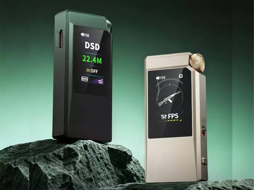 Les deux finitions du DAC portable FiiO QX11 posées sur un rocher, la version vert foncé affichant DSD 22.4M sur son écran LCD couleur et la version or affichant le preset gaming FPS, molette de volume crantée et double port USB-C visibles