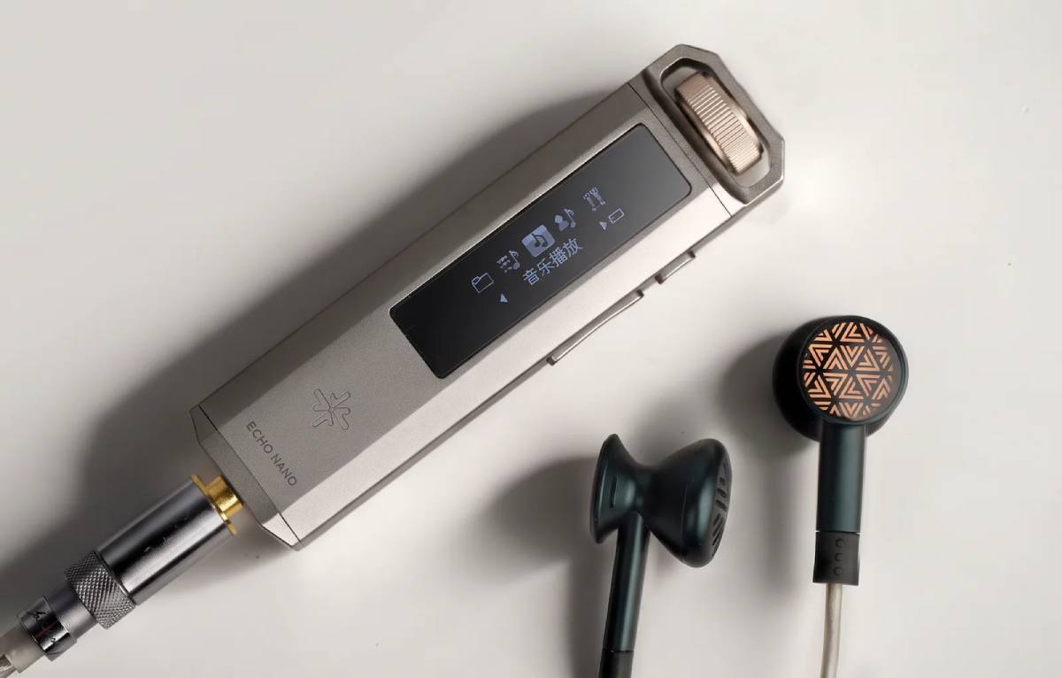 Baladeur Hi-Res FiiO Snowsky Echo Nano en finition titane avec molette dorée, écran OLED affichant le menu de navigation, câble jack 3,5 mm doré branché et écouteurs earbuds posés à côté
