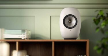 Enceinte active sans fil KEF LS LUXE Mineral White posée sur un meuble dans un salon