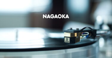 Cellule phono Nagaoka de la série MP vue de trois quarts, corps plastique moulé, cantilever conique en alliage d'aluminium et diamant elliptique visible, avec son diamant de rechange JN-P posé à côté dans son support de protection