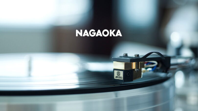 Cellule phono Nagaoka de la série MP vue de trois quarts, corps plastique moulé, cantilever conique en alliage d'aluminium et diamant elliptique visible, avec son diamant de rechange JN-P posé à côté dans son support de protection