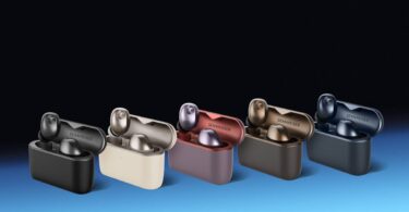 Écouteurs Sennheiser Momentum True Wireless 5 en finition Graphite posés devant leur boîtier de charge Qi au format vertical, avec le transducteur TrueResponse 7 mm et les grilles de microphones visibles sur la face externe des écouteurs