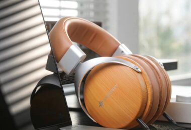 Casque SNOWSKY Nature en finition bois abricot posé sur un bureau près d'une fenêtre, coques circum-aurales fermées à motif bois clair avec logo SNOWSKY, arceau en simili cuir marron, fourches aluminium argenté et double câble détachable 3,5 mm visible