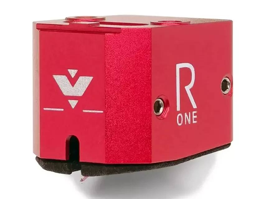 Cellule MC Vertere Ruby One isolée sur fond blanc en vue trois quarts, corps aluminium anodisé rouge avec logo Vertere gravé, marquage R ONE, vis pointes latérales du montage générateur, trous filetés M2.5 sur le dessus et amortisseur noir sous le corps