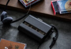 Baladeur cassette Amadana CP10 noir avec panneau avant fumé semi-transparent laissant voir la cassette, dragonne tressée noire, casque filaire rétro à coussinets en mousse grise et boîtiers de cassettes audio