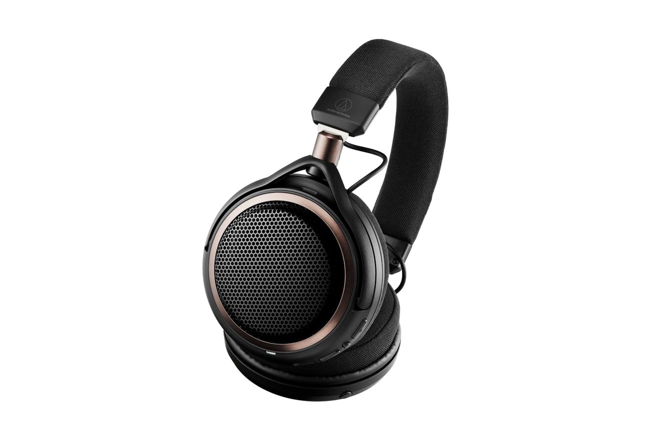 Packshot du casque ouvert Bluetooth Audio-Technica ATH-AL5NC noir sur fond blanc, avec grille hexagonale, anneau bronze, boutons de commande sur la coque droite et arceau textile siglé Audio-Technica
