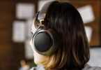 Femme de profil portant le casque ouvert sans fil Audio-Technica ATH-AL5NC, avec grille hexagonale métallique, arceau textile, logo Audio-Technica et accents bronze, dans un intérieur chaleureux