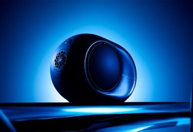 Enceinte connectée Devialet Phantom Ultimate 98 dB Pulse Blue de profil sur fond bleu lumineux, avec flasque latérale miroir, woofer HBI latéral, logo Devialet et commandes tactiles sur le dessus