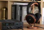 Casque planaire ouvert FiiO FT15 avec coques en noyer noir massif, grilles noires et logo doré, posé sur un support en bois à côté d'un DAC ampli casque de bureau FiiO à écran couleur, dans une bibliothèque