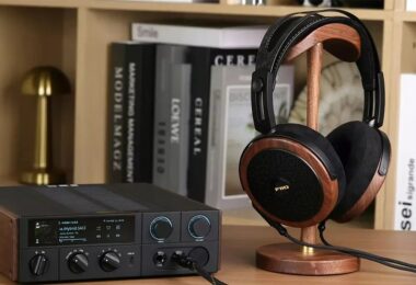 Casque planaire ouvert FiiO FT15 avec coques en noyer noir massif, grilles noires et logo doré, posé sur un support en bois à côté d'un DAC ampli casque de bureau FiiO à écran couleur, dans une bibliothèque