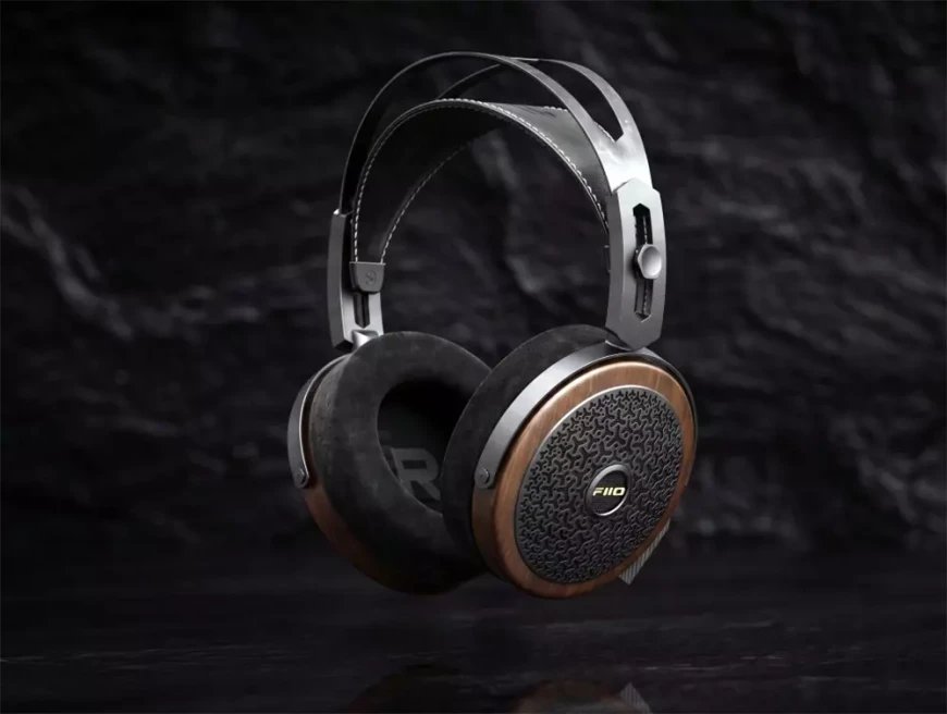 Casque planaire ouvert FiiO FT15 en vue de trois quarts sur fond de pierre sombre, avec coques en noyer massif, grilles ajourées noires, coussinets en suédine, arceau métallique et bandeau de suspension en cuir surpiqué