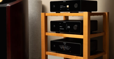 Trois appareils Michi Prestige empilés, lecteur CD Q430, préampli P430 et ampli S430, avec façades noires, écrans TFT couleur et vumètre, près d'une enceinte colonne