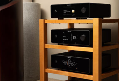 Trois appareils Michi Prestige empilés, lecteur CD Q430, préampli P430 et ampli S430, avec façades noires, écrans TFT couleur et vumètre, près d'une enceinte colonne