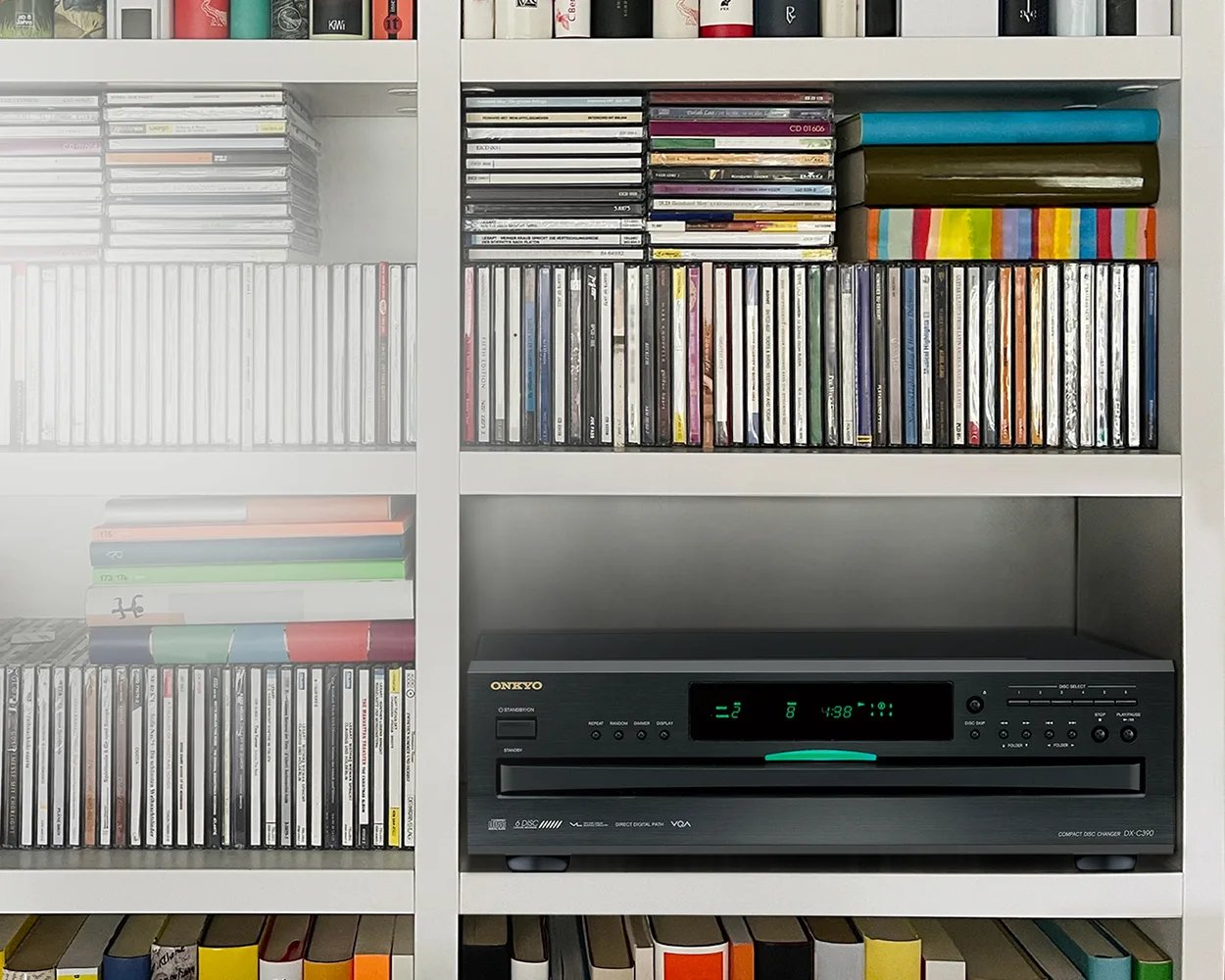 Changeur CD Onkyo DX-C390 noir, afficheur vert allumé, installé dans une étagère blanche au milieu d'une collection de CD rangés sur la tranche et en piles