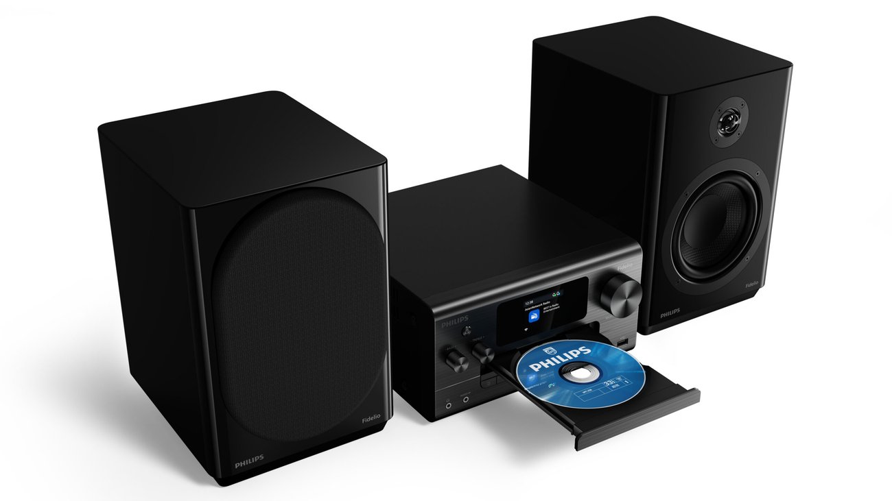 Micro-chaîne Philips Fidelio FA7 vue en plongée, tiroir CD motorisé ouvert avec un disque, écran couleur, molettes basses et aigus, port USB, entre une enceinte avec grille et une enceinte à tweeter titane apparent