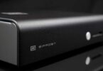 DAC Schiit Bifrost 3 en finition argent vu de trois quarts, façade en aluminium brossé avec logo Schiit, inscription Bifrost, bouton de sélection et nouvelle barre lumineuse d'indication des entrées