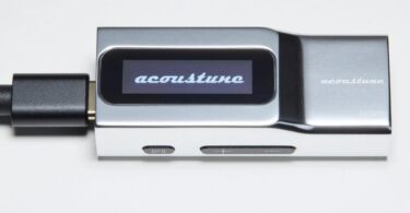 Dongle DAC USB-C Acoustune AS2200 en aluminium argent vu de profil, écran OLED affichant le logo acoustune, câble USB-C branché